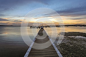 Timber jetty leading to colourful sky at dusk