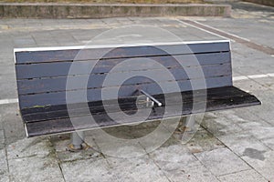 Timber metal bench seat with center arm rests on hostile design prevents the homeless from laying down