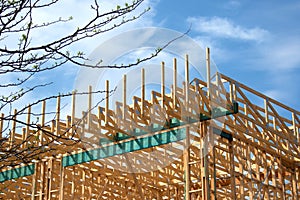 Timber trusses and a wall frame set against cloudy blue sky