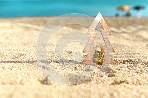 Timber wooden Christmas tree on a sand on the tropical beach near ocean, summer Christmas and winter holyday concept