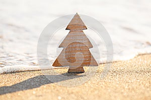 Timber wooden Christmas tree on a sand on the tropical beach near ocean, summer Christmas and winter holyday concept