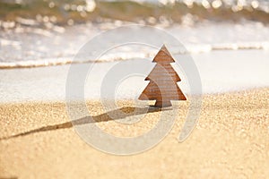 Timber wooden Christmas tree on a sand on the tropical beach near ocean, summer Christmas and winter holyday concept