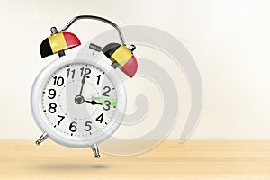 Time change in Belgium, spring forward. Summer time concept, over white background. A white alarm clock with a minute