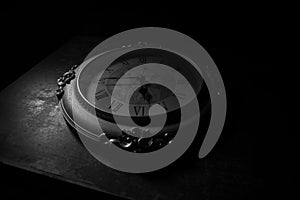 Time concept. Big vintage round clock on wooden table with abstract light