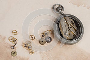 Time concept - broken vintage pocket watch on dirty paper background
