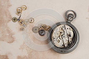 Time concept - broken vintage pocket watch on dirty paper background