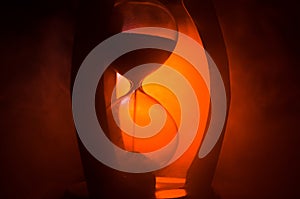 Time concept. Silhouette of Hourglass clock and smoke on dark background with hot yellow orange red blue cold back lighting, or sy