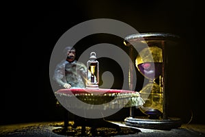 Time concept. Silhouette of a man standing between hourglasses with smoke and lights on a dark background