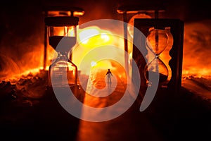 Time concept. Silhouette of a man standing between hourglasses with smoke and lights on a dark background. Surreal decorated