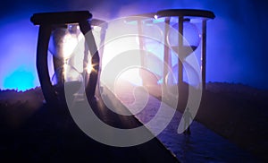 Time concept. Silhouette of a man standing between hourglasses with smoke and lights on a dark background. Surreal decorated