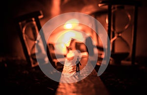 Time concept. Silhouette of a man standing between hourglasses with smoke and lights on a dark background. Surreal decorated