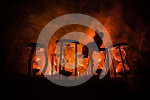 Time concept. Silhouette of a man standing between hourglasses with smoke and lights on a dark background. Surreal decorated pictu