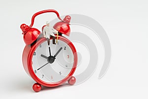 Time counting down for retirement concept, miniature happy senior old man sitting on big red alarm clock on white background with