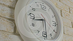 Time eight hours thirty minutes. Timelapse. Round white clock hanging on brick wall.