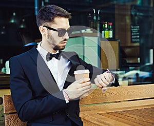 Time. Expectation. Coffee break. man, business man in a business suit and cup of coffee looking at the clock. City cafe