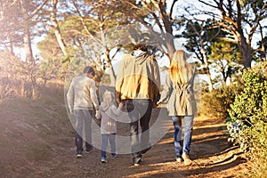 Time for a family adventure. Rearview shot of a young family walking along a forest trail.