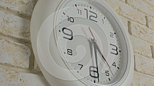 Time four hours thirty minutes. Timelapse. Round white clock hanging on brick wall.