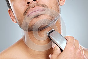 Time for a fresh look. a man shaving his beard with an electric razor.