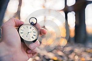 Time goes by: vintage watch outdoors, hand-held; wood and leaves