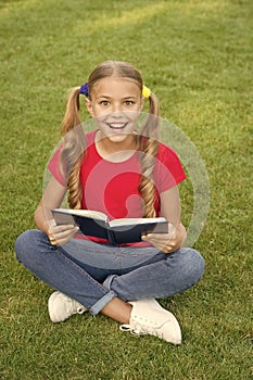 Time for great stories. Little child reading book outdoors. Schoolgirl read stories while relaxing green lawn. Cute