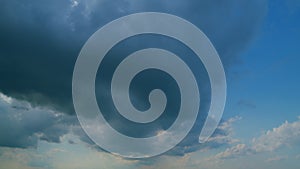 Time lapse. Background of dark dramatic sky with stormy clouds. Moving white puffy clouds on blue sky.