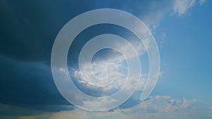 Time lapse. Background of dark dramatic sky with stormy clouds. Moving white puffy clouds on blue sky.