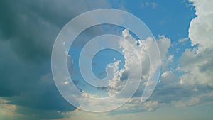 Time lapse. Background of dark dramatic sky with stormy clouds. Moving white puffy clouds on blue sky.