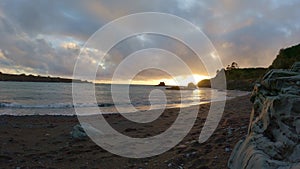 Time lapse on beach as sun sets behind bluff and clouds move over