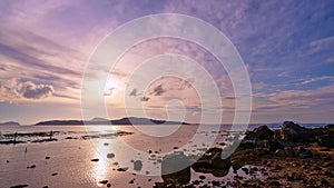 Time lapse beautiful sunrise sky over island at tropical sea. coral reef during low tide water in the sea with rocks in the foregr