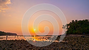 Time lapse beautiful sunset sky over island at Tropical sea. Coral reef during low tide water in the sea with rocks in the foregro