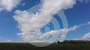 Time-lapse blue sky, billowing white clouds, beautiful sunny day, green forest.