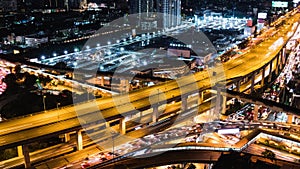 Time-lapse of car traffic transportation on highway, road intersection, sky train railway, with under construction site at night