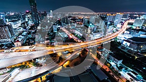 Time-lapse of car traffic transportation on highway road, toll gate at night. Cityscape view with construction crane on building