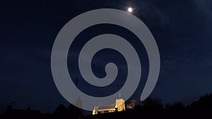 Time-lapse of clouds passing floodlit church as night falls