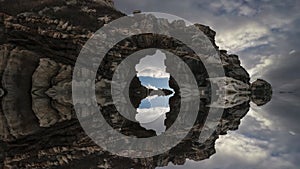 Time lapse, clouds run behind the rocks, reflections