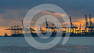 Time lapse of clouds and sky over shipping and cargo facilities along glistening Singapore Straits at sunset 4k