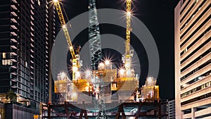 Time-lapse of crane and construction worker in under construction building site at night