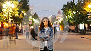 Time-lapse of good-looking woman towny in denim clothing standing alone in the street among crowds of people and looking