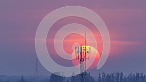 Time lapse of the large orange sunset with antenna, skyline sunrise silhouette with flare.