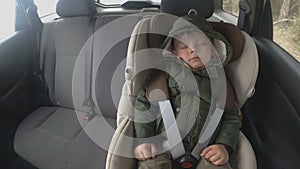 Time lapse. Little boy in the backseat of a car is asleeping. The car is going on a bad road. Travel with baby