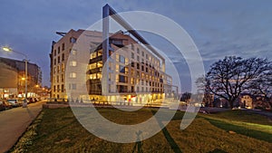 Time lapse of modern smart building with people passing by at dusk