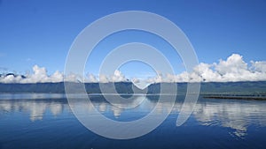 Time lapse, movement of clouds over blue hills and lake