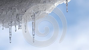 Time-lapse movie of a blue sky and drifting clouds looking through the transparent icicles.