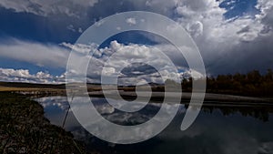 Time lapse of moving clouds over the river. Flowing water with mountains in the background, majestic Mongolian landscape