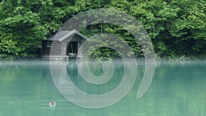 Time lapse of mysterious fog around a small boathouse on a lake in the forest.