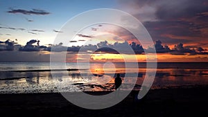 Time-lapse of people on the beach during dark orange cloudy sunset