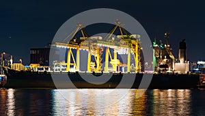 Time-lapse of shipping port with cargo container ship, crane, in Asia city at night. Logistic industry, industrial business