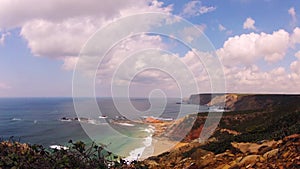 Time-lapse shot of a beach with rocks, sand, waves and fast moving clouds