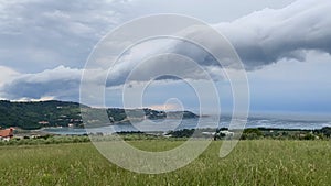 Time lapse of storm clouds running across the sky against the background of the sea and green hills on coast. Adriatic seaside