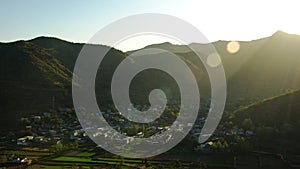 Time-lapse of sunrise in village at mountain foot, sun lens flare